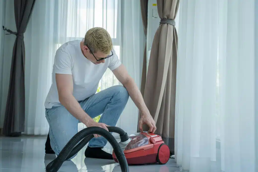 Man repariert Staubsauger,Father looking at broken vacuum cleaner and fixing it at home.